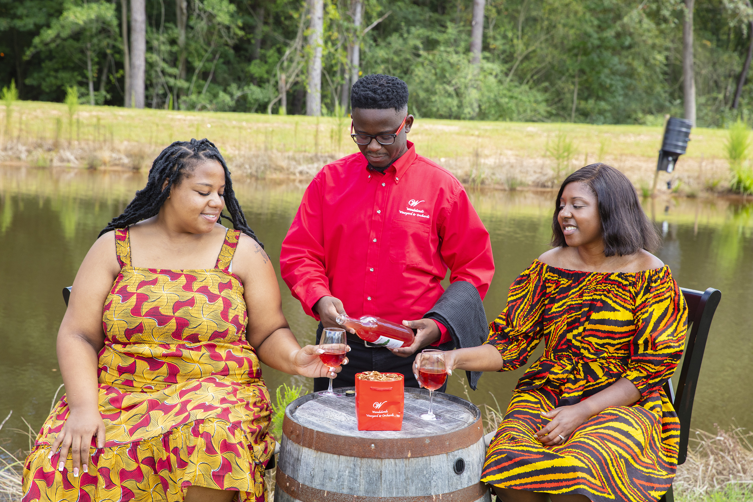 Guests gathered around a barrel table beside the pond at Wandalands Vineyard & Orchards